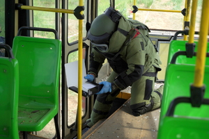 policyjny pirotechnik ubiera specjalistyczny kombinezon i udaje się do tramwajów, gdzie sprawdza podejrzane pakunki