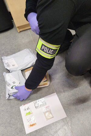 ujęcie na paczki oraz woreczki strunowe z zawartością podejrzanych substancji, które rozkłada policjant