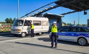 Policjant kontroluje kierowcę pod kątem trzeźwości, a policjantka stoi w pobliżu radiowozu