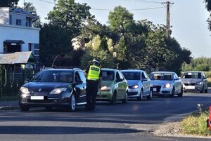 Policjant kontroluje kierowcę pod kątem trzeźwości, a za nimi stoją cztery inne auta