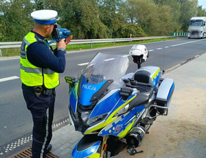 Policjant RD mierzy prędkość obok stoi oznakowany motocykl