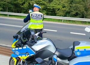 Policjant RD mierzy prędkość obok stoi oznakowany motocykl