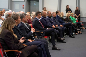Inauguracja programu „Świadomy Senior – Bezpieczny Senior” zaproszeni goście oraz Seniorzy siedzą na krzesłach w auli