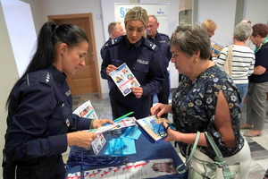 przy stoisku policyjnym stoją seniorzy, policjanci rozdają im przegotowane dla nich gadżety