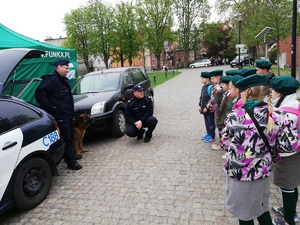 Teren  Wyspy Młyńskiej w Bydgoszczy. W tle drzewa i kamienice. Policjanci z harcerzami podczas prelekcji.