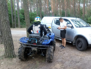 Policjant i użytkownik Quada podczas kontroli w terenie leśnym.