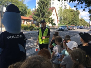 Policjantka tłumaczy dzieciom, jak należy pokonywać przejście dla pieszych.