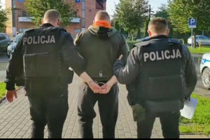 policjanci prowadzą zatrzymanego mężczyznę