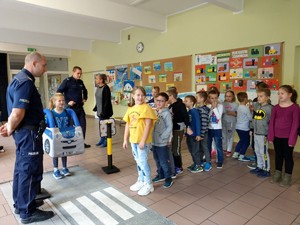 Zajęcia praktyczne przy pomocy miasteczka ruchu drogowego zorganizowane z dziećmi na korytarzu szkolnym.