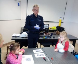 Technik kryminalistyki podczas prelekcji dla dzieci.