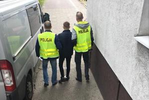 policjanci prowadzą zatrzymanego skutego kajdankami