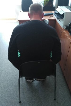 zatrzymany skuty kajdankami siedzi na krześle