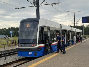 Policjanci wraz z innymi osobami wsiadają do tramwaju.