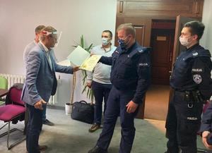 Burmistrz Koronowa Patryk Mikołajewski wręcza podziękowania policjantowi ogniwa wodnego.