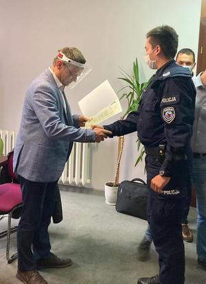 Burmistrz Koronowa Patryk Mikołajewski wręcza podziękowania policjantowi ogniwa wodnego.(3)