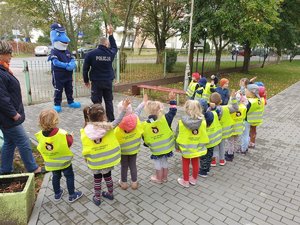 Policjant podczas zajęć z dziećmi przez budynkiem placówki.