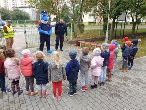 policjant i dzieci podczas rozmowy przed budynkiem przedszkola.