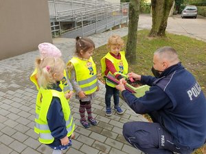 Policjant wręcza dzieciom odblaski