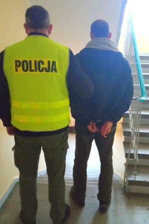 policjant prowadzi zatrzymanego skutego kajdankami