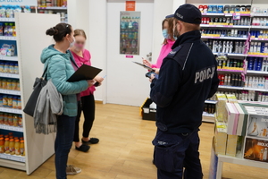 policjant i dwie pracownice sanpeidu kontrolują jeden z sklepów w galerii handlowej