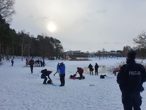 Policjant patrzy w stronę osób przebywających w rejonie jeziora