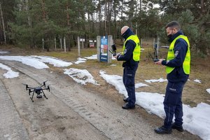 policjanci stoją koło drona z urządzeniem do sterowania