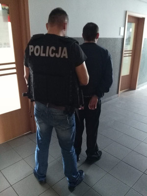 Policjant prowadzi zatrzymanego.