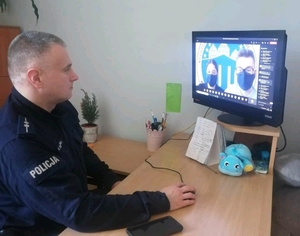 Policjant siedzi przy biurku przed komputerem podczas zajęć online- zdjęcie nr 2.