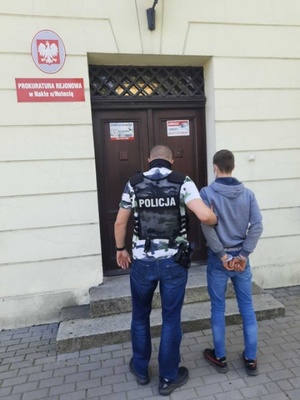 Policjant prowadzi 3 sprawcę do prokuratury w Nakle nad Notecią.
