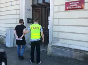 Policjant wraz z zatrzymanym przed wejściem do prokuratury.