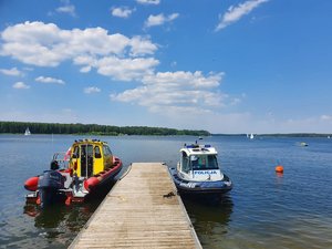 Policyjna łódź motorowa oraz łódź ratowników Wopr-u zacumowane przy pomoście na Zalewie Koronowskim.