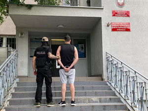 Policjant prowadzi zatrzymanego po schodach prowadzących do Komisariatu na bydgoskich Wyżynach.