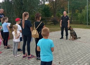 Policjant i pies podczas pogadanki z uczestnikami festynu/.