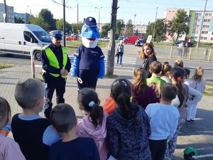 Policjanci rozmawiają z dziećmi po przejściu przez pasy na dwóch jezdniach.