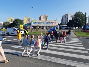 Policjanci nadzorują przechodzenie uczniów przez przejście dla pieszych.