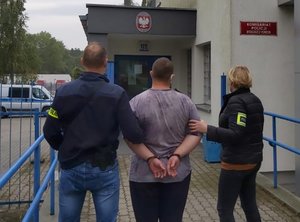 Policjanci idą z zatrzymanym do budynku komisariatu w Fordonie.