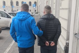 nieumundurowany policjant prowadzi zatrzymanego skutego kajdankami