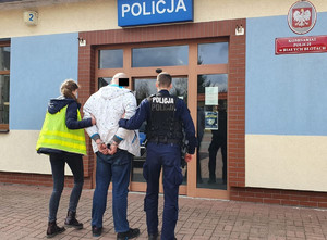 Policjanci prowadzą zatrzymanego do komisariatu w Białych Błotach.