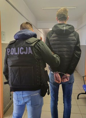 Policjant prowadzi zatrzymanego.