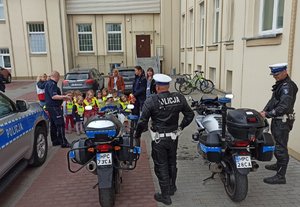 policjanci ruchu drogowego z motocyklami oraz stojące przy nich dzieci