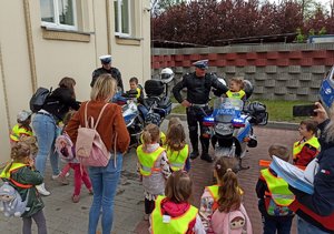 dwoje dzieci siedzi na motocyklach policyjnych p, przy nich stoją policjanci oraz inne dzieci