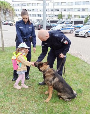 dziewczynka w obecności policjantki i policjanta głaszcze psa policyjnego