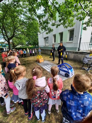 Policjanci i dzieci podczas pogadanki w terenie zielonym.