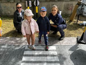 dzieci przechodzą przez pasy miasteczka ruchu drogowego pod okiem policjantki i policyjnego profilaktyka