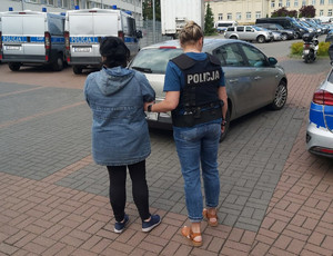 Policjantka prowadzi zatrzymaną kobietę.