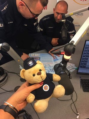 policjanci siedzą w studiu radia, redaktorka trzyma policyjnego misia