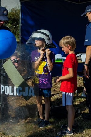 Dzieci przymierzają elementy policyjnego umundurowania.