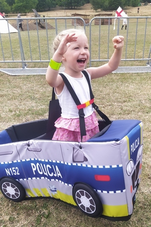 dziewczynka ma założony autochodzik z napisem Policja
