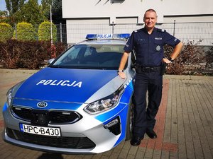 Policjant stoi przy radiowozie.