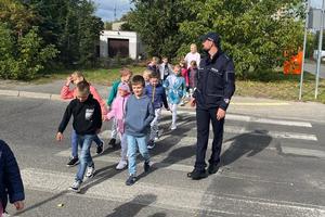 policjant przeprowadza dzieci przez przejście dla pieszych